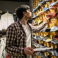 Shoe and clothing store employee using a clipboard to check stock, an example of outdated and inefficient data capture.