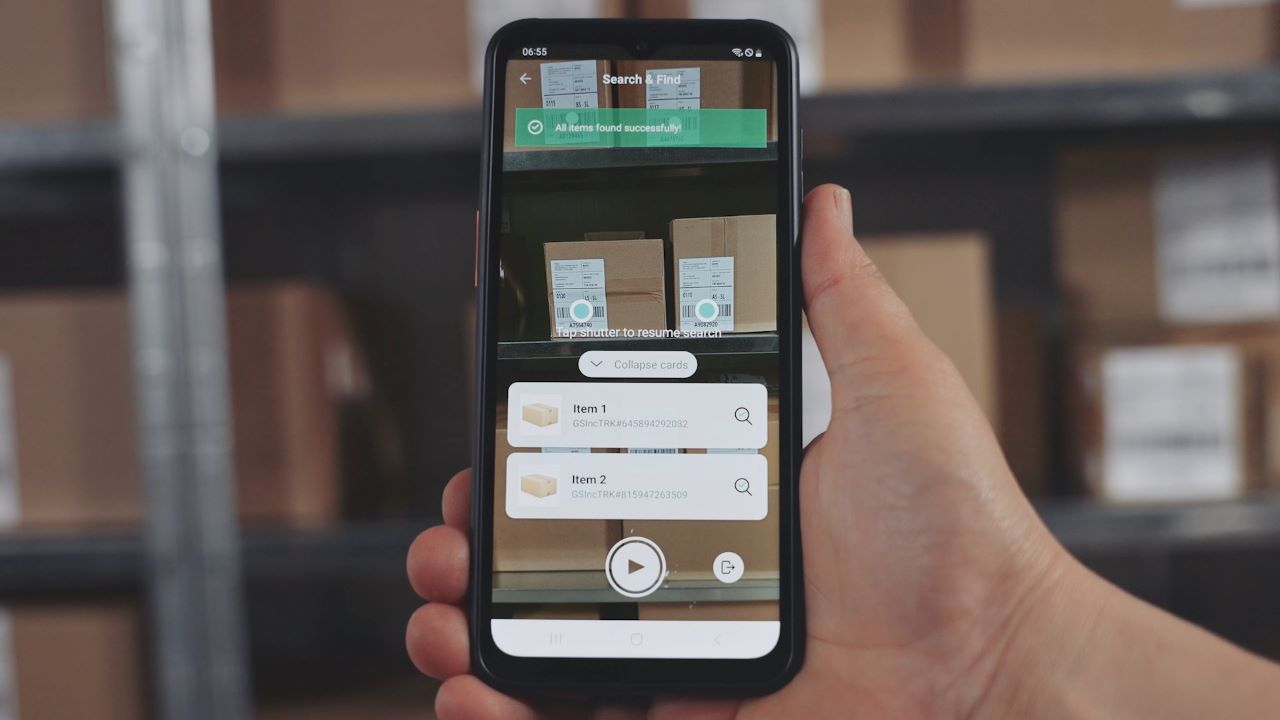 Logistics worker using augmented reality (AR) on a smartphone to idenitfy one cardboard box among many on a shelf